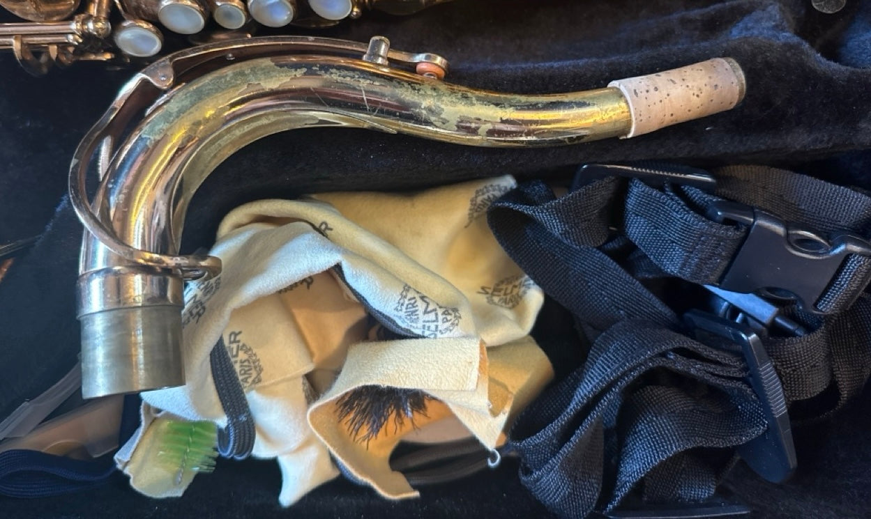 Close-up of the original Selmer Mark VI tenor saxophone neck with cork, showing natural wear and included shoulder harness accessories